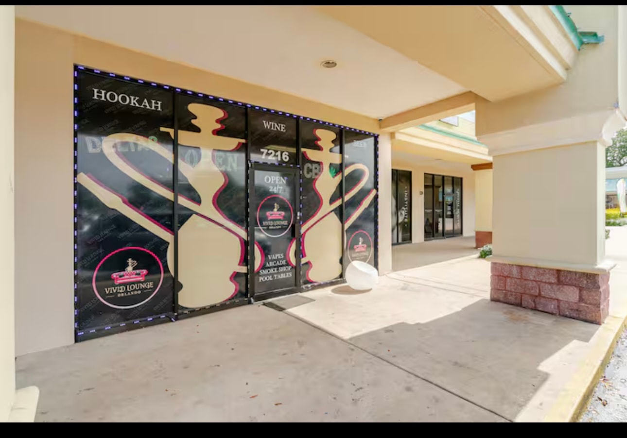 The Vivid Smoke Shop & Lounge storefront at 7216 W Colonial Drive, its windows wrapped in black vinyl with a hookah silhouette and the Vivid Lounge Orlando roundel.