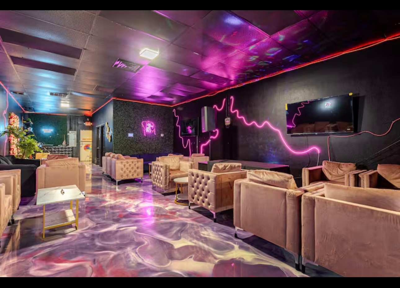 Another lounge room, low-lit, with velvet armchairs grouped around tables on the poured floor.