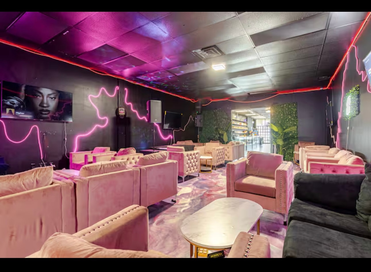The lounge looking back toward the shop floor, velvet seating either side of a marble-topped table.