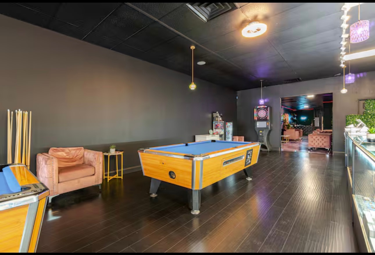 A pool table with the cue rack on the wall and a dartboard machine by the doorway through to the lounge.